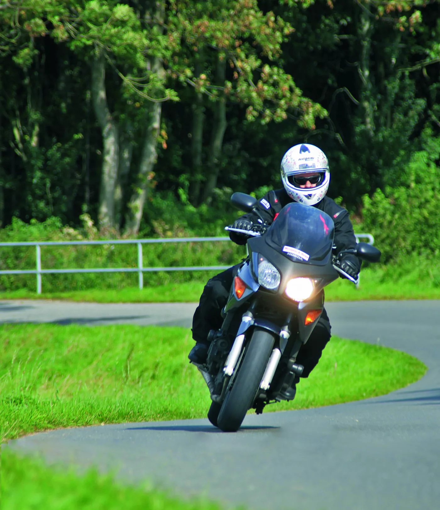 Motorrad in einer Kurve auf einer Landstraße zwischen Wiesen Motorrad in einer Kurve auf einer Landstraße zwischen Wiesen